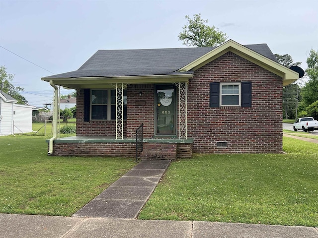 - view of front of home featuring brick siding, a front yard, covered porch, and a shingled roof