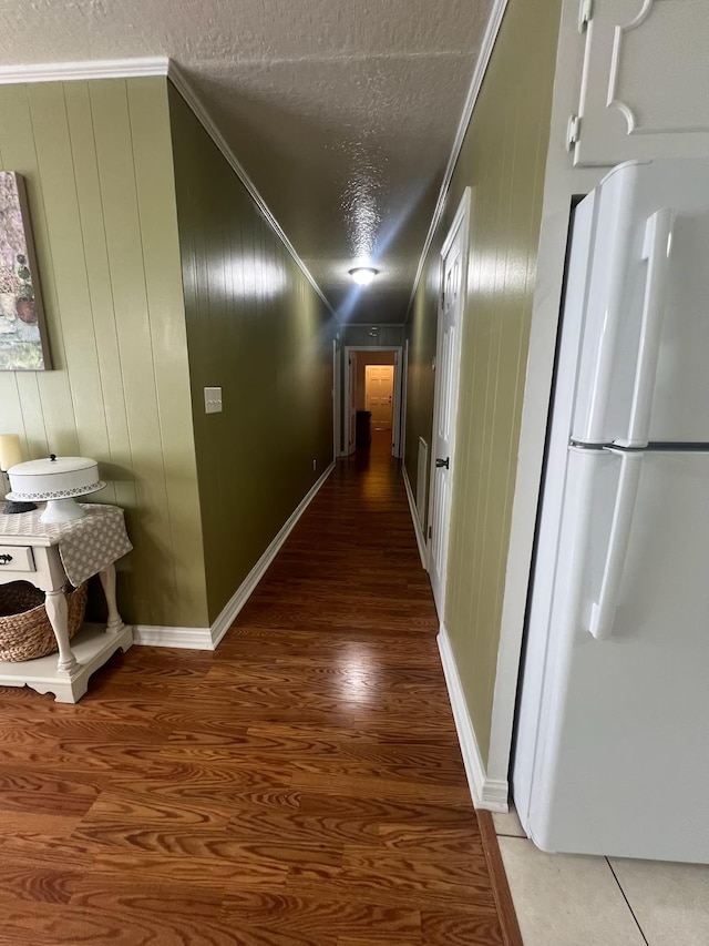  - hallway featuring a textured ceiling, crown molding, wood finished floors, and baseboards