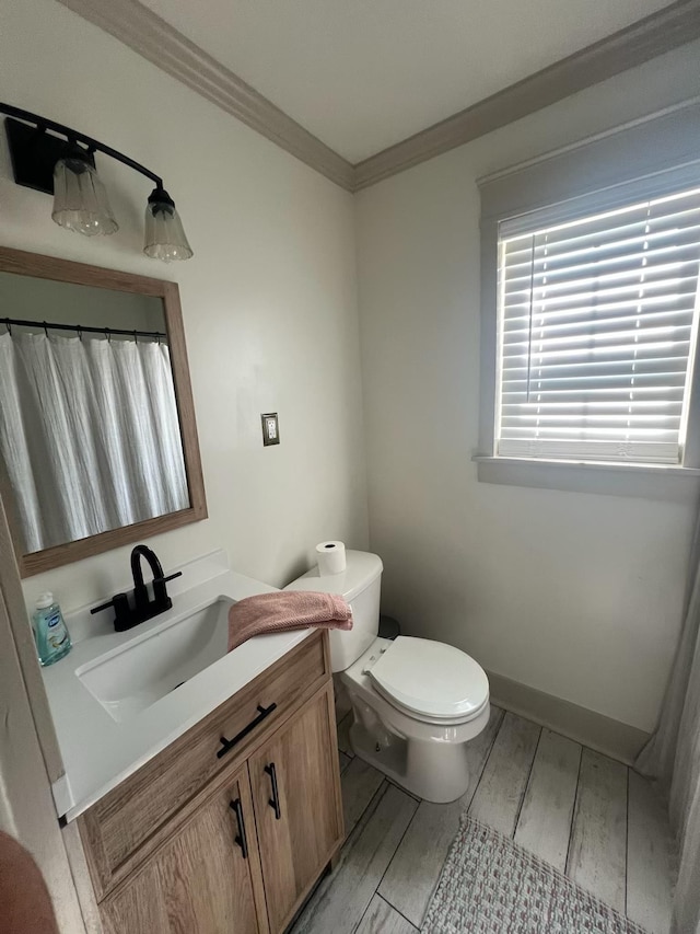  - full bath featuring vanity, toilet, crown molding, wood finished floors, and baseboards