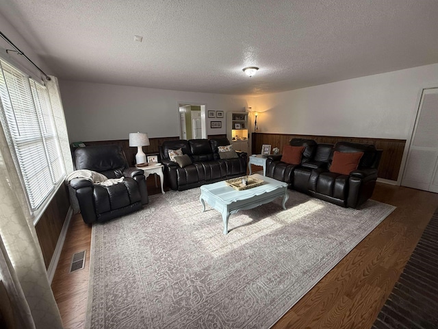  - living area with wood finished floors, a textured ceiling, a wainscoted wall, and wood walls