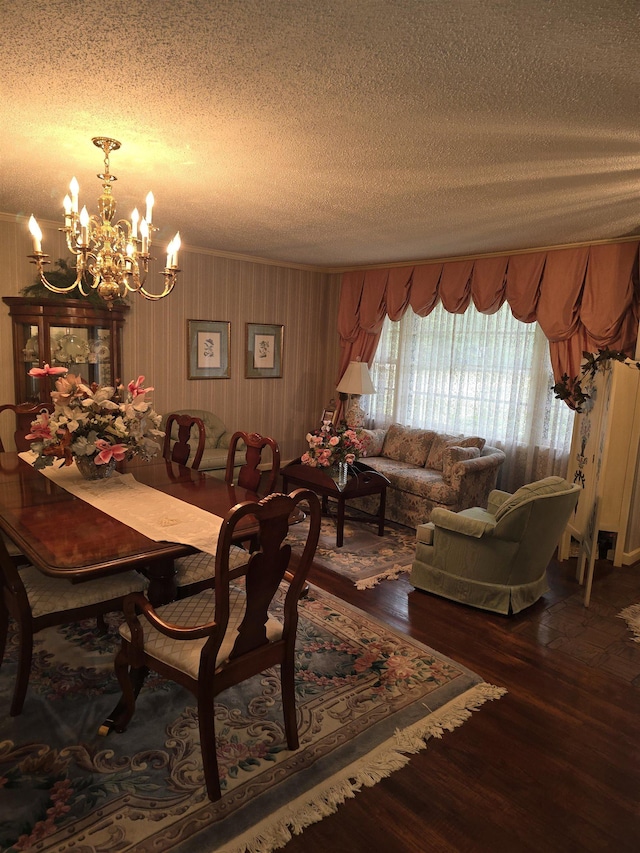 dining area featuring a notable chandelier, crown molding, dark wood-type flooring, and a textured ceiling