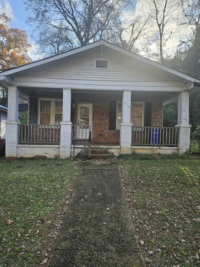 bungalow featuring covered porch and a front yard