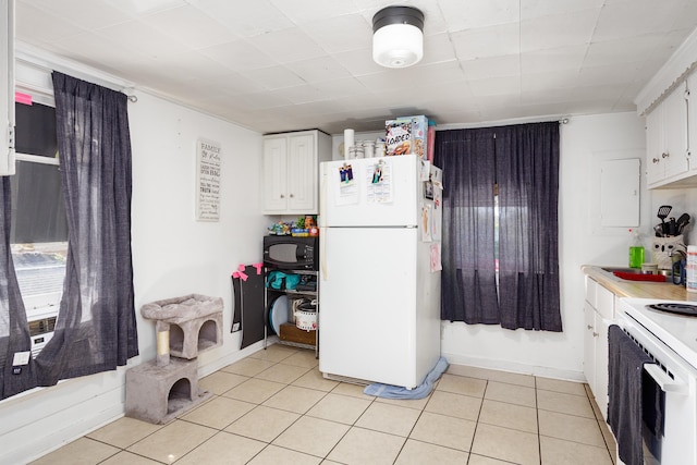  - kitchen featuring white appliances, white cabinets, light tile patterned floors, and light countertops