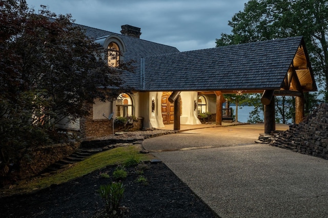 exterior space featuring a chimney, driveway, and stucco siding