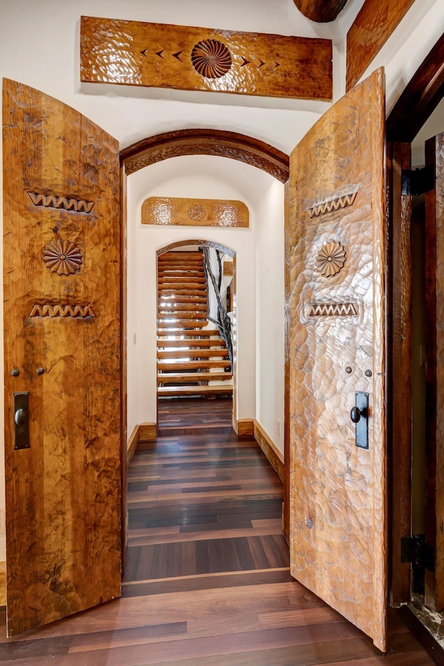 wine room with baseboards, arched walkways, and wood finished floors