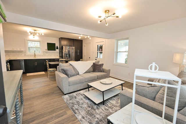 living room featuring light wood-type flooring, sink, and an inviting chandelier