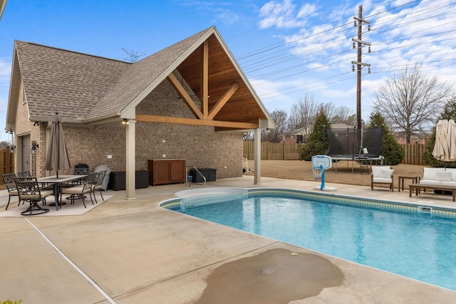 view of pool featuring a patio area, a fenced backyard, and a trampoline