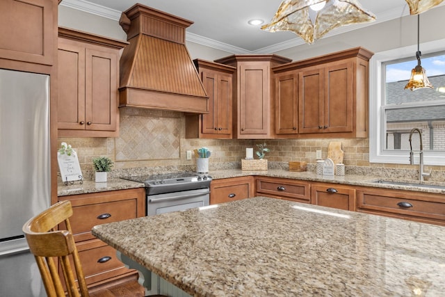 kitchen with ornamental molding, appliances with stainless steel finishes, premium range hood, and a sink