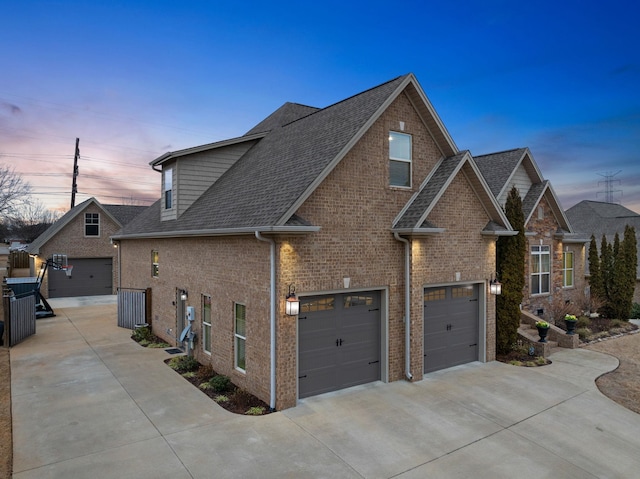 property exterior at dusk with a garage, brick siding, and driveway