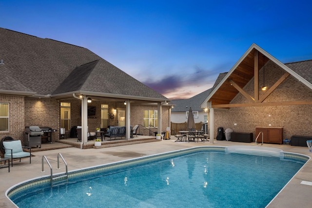 pool at dusk with a fenced in pool, fence, outdoor lounge area, and a patio area