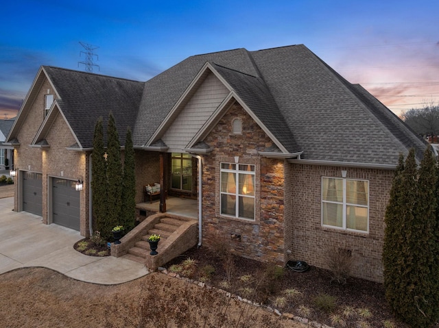 view of front of house featuring driveway, stone siding, roof with shingles, a garage, and brick siding