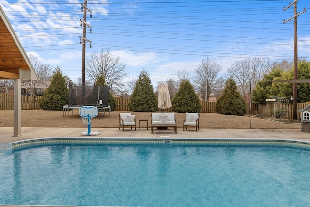 view of pool with a trampoline, a fenced in pool, and a fenced backyard