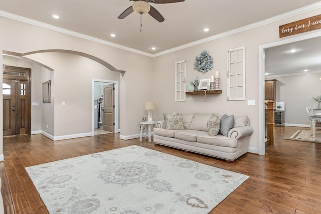 living area featuring baseboards, wood finished floors, arched walkways, and ornamental molding