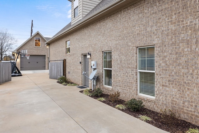 view of side of property featuring brick siding, an outdoor structure, and a garage