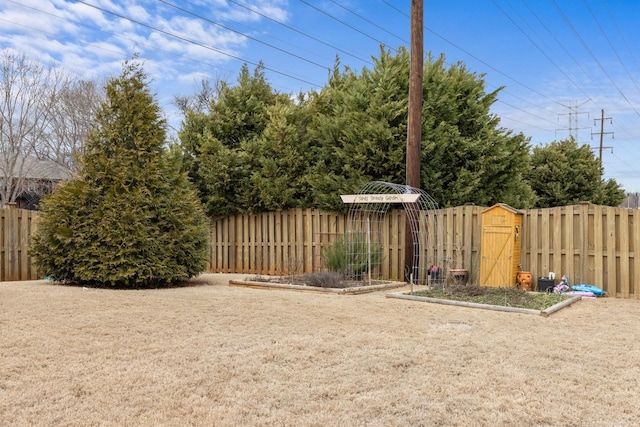 view of yard with an outdoor structure, a storage shed, and a fenced backyard