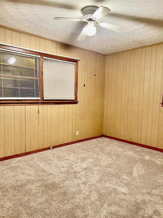 empty room with light carpet, a ceiling fan, and baseboards