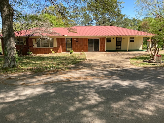 single story home featuring metal roof, a front yard, driveway, and brick siding