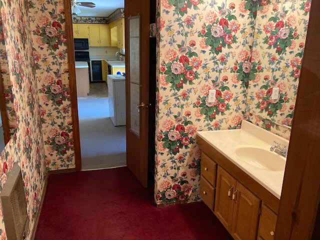 bathroom featuring vanity, wallpapered walls, and washer / dryer