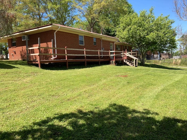 back of property with a lawn, brick siding, and a wooden deck
