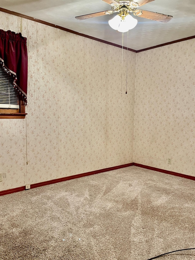 carpeted empty room featuring ceiling fan, crown molding, and wallpapered walls