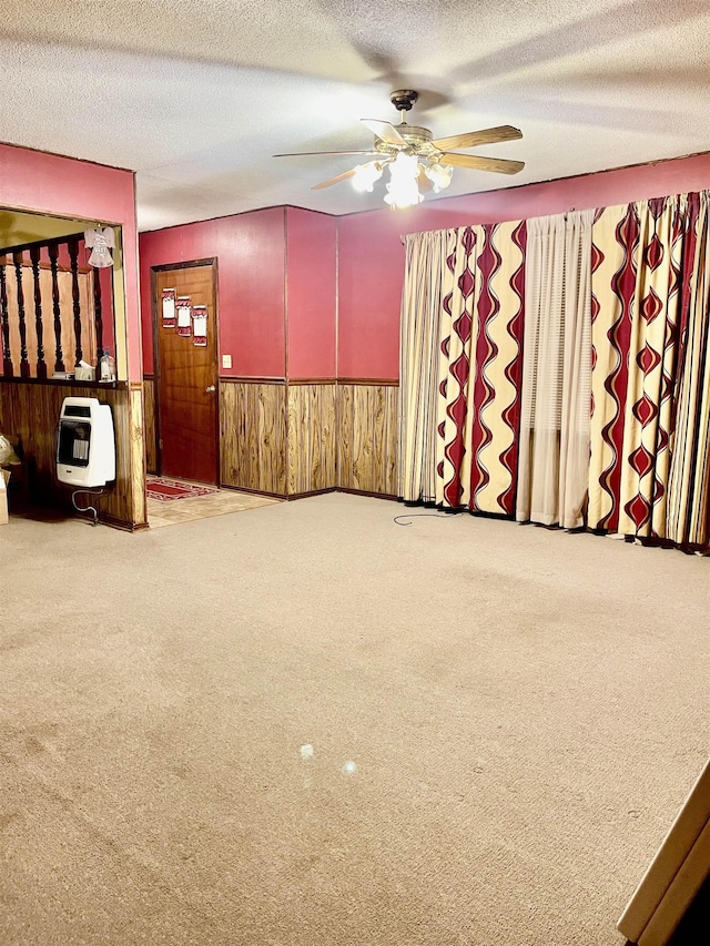 interior space featuring carpet, a wainscoted wall, heating unit, wood walls, and a textured ceiling