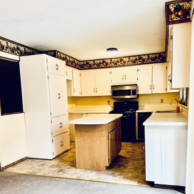  - kitchen with stainless steel microwave, a sink, black range oven, light countertops, and a center island