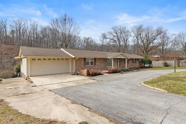 single story home with aphalt driveway, an attached garage, fence, and brick siding