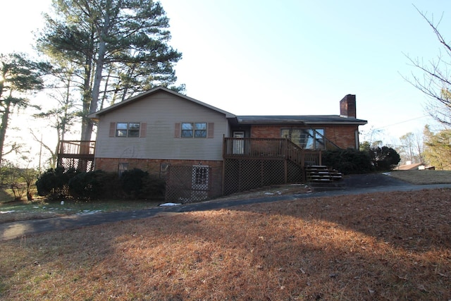 - back of property featuring brick siding, a chimney, and a deck