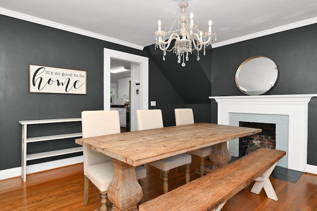 dining space with a fireplace, hardwood / wood-style floors, a chandelier, and ornamental molding