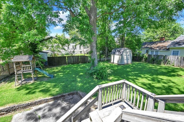 view of yard featuring a storage shed, a playground, and a wooden deck