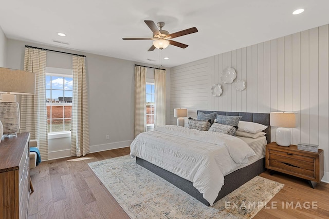 bedroom featuring hardwood / wood-style flooring, ceiling fan, and wooden walls