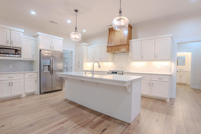 kitchen with white cabinetry, stainless steel appliances, sink, custom exhaust hood, and pendant lighting