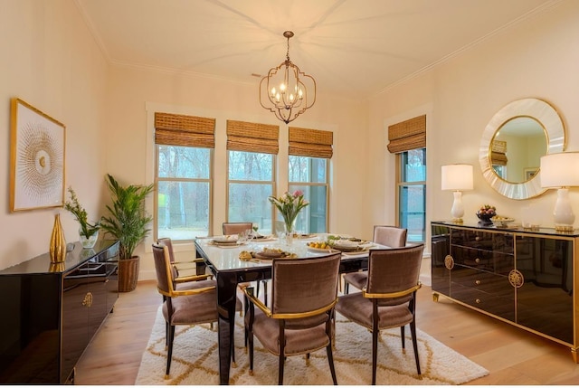 dining room featuring a notable chandelier, ornamental molding, and light wood-type flooring