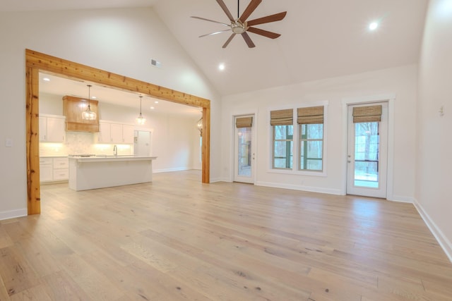 unfurnished living room with light hardwood / wood-style floors, high vaulted ceiling, and ceiling fan