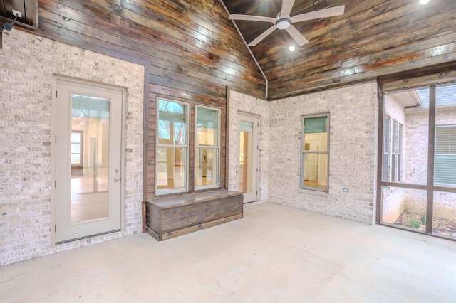 spare room featuring ceiling fan, vaulted ceiling, and brick wall