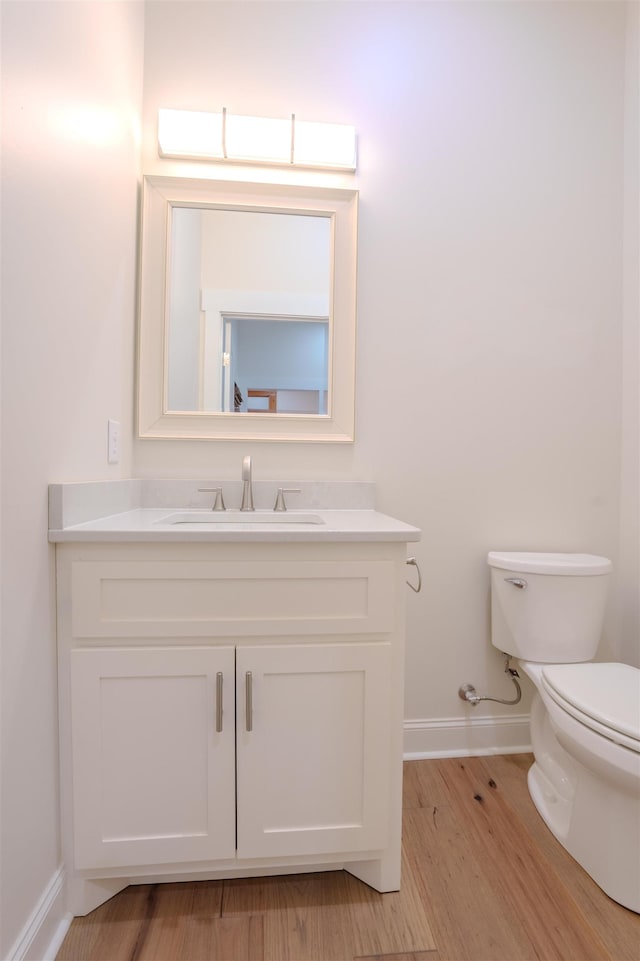 bathroom with hardwood / wood-style flooring, vanity, and toilet