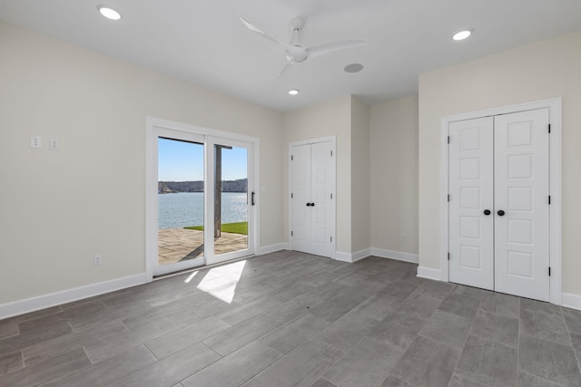 unfurnished bedroom with a water view, access to exterior, baseboards, and recessed lighting