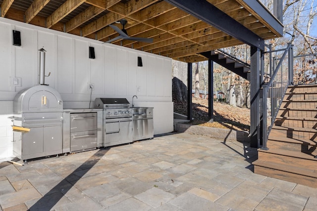 view of patio / terrace with exterior kitchen, a grill, ceiling fan, and stairs