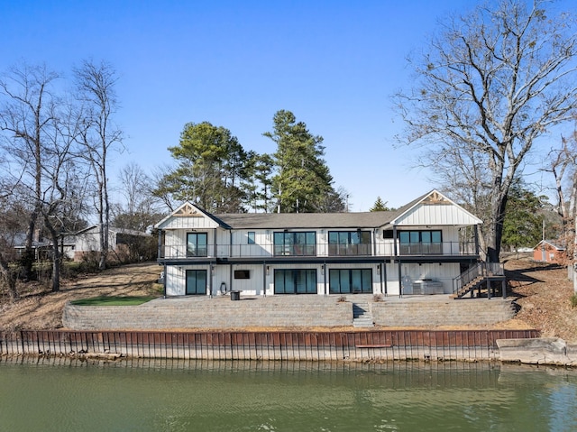 rear view of property featuring stairs, board and batten siding, a water view, and a balcony