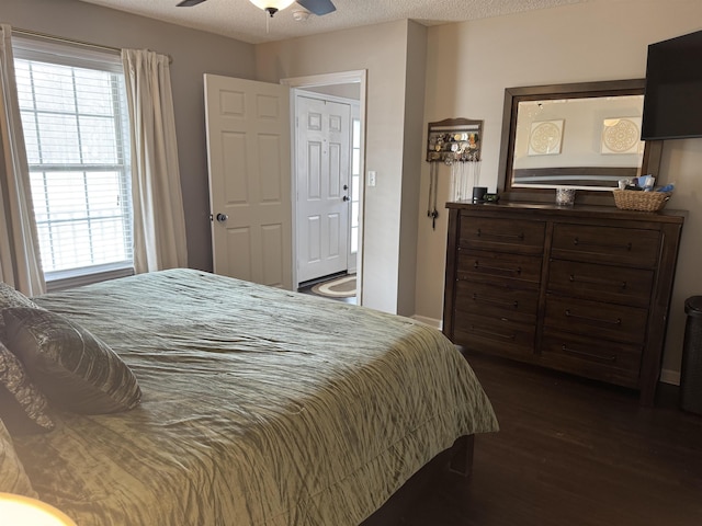 bedroom featuring multiple windows, ceiling fan, dark hardwood / wood-style flooring, and a textured ceiling