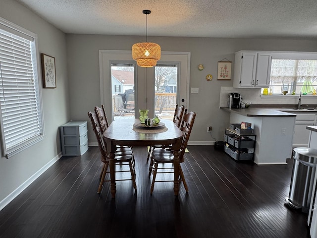 dining area featuring a textured ceiling, a wealth of natural light, dark wood-type flooring, and sink