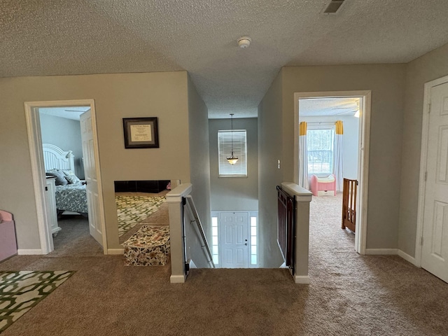 hall with carpet flooring and a textured ceiling