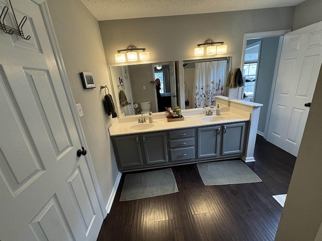 bathroom featuring vanity, a textured ceiling, hardwood / wood-style flooring, and toilet