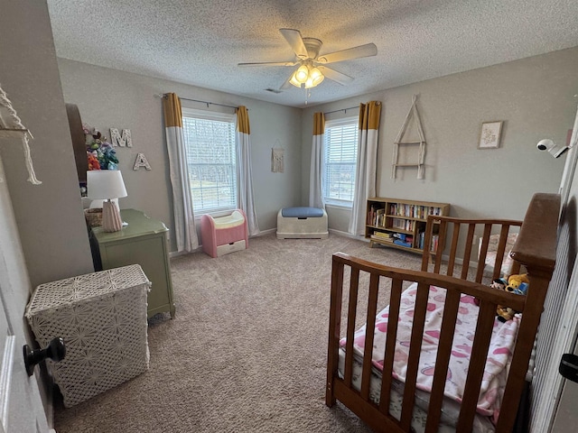 bedroom featuring carpet, ceiling fan, a textured ceiling, and a nursery area