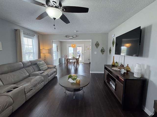 living room featuring a textured ceiling, ceiling fan, and dark wood-type flooring