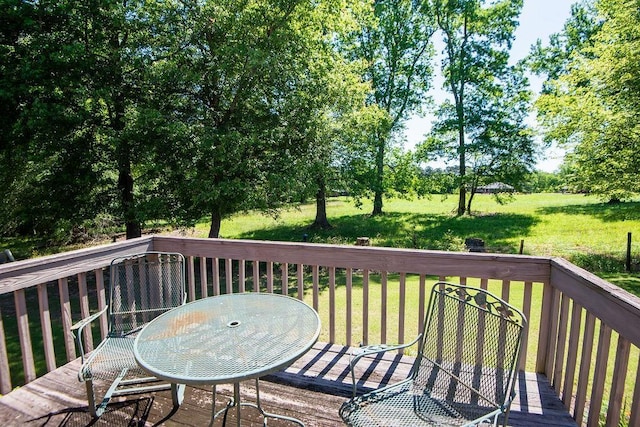  - wooden deck featuring a yard, outdoor dining space, and view of wooded area