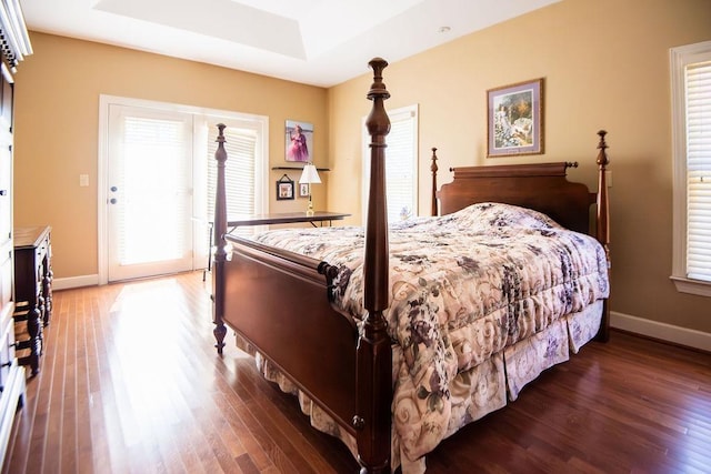  - bedroom with wood finished floors, baseboards, a raised ceiling, and access to outside