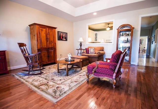  - living area with wood finished floors, baseboards, a tray ceiling, and recessed lighting
