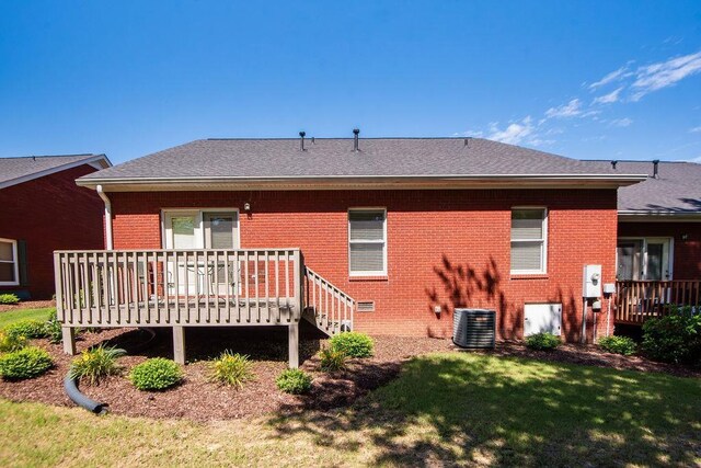  - back of property with brick siding, central AC, a wooden deck, a lawn, and a shingled roof