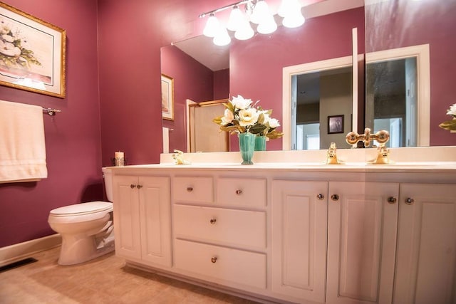  - full bathroom featuring double vanity, a shower with shower door, toilet, baseboards, and tile patterned flooring